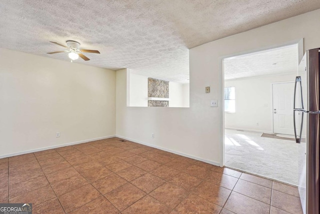 empty room with ceiling fan, a textured ceiling, and tile patterned floors