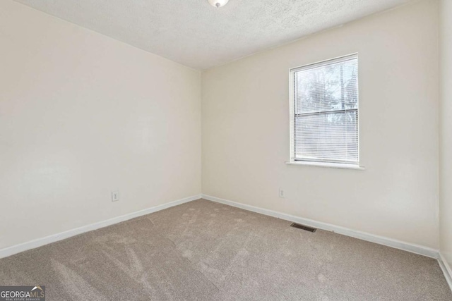 spare room featuring a textured ceiling and carpet