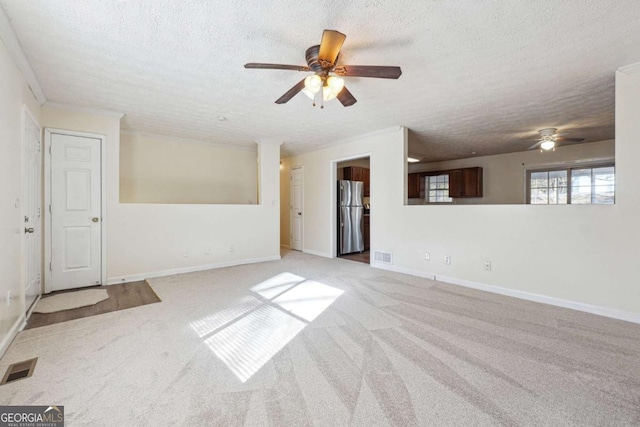 spare room with ceiling fan, light colored carpet, crown molding, and a textured ceiling