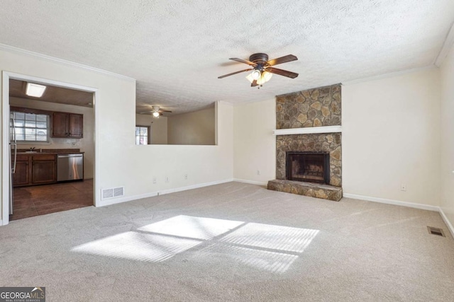 unfurnished living room featuring a textured ceiling, ceiling fan, carpet, and a stone fireplace