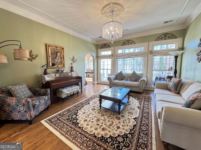 living room with wood-type flooring, an inviting chandelier, and ornamental molding