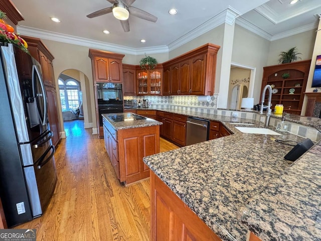 kitchen with a kitchen island, sink, crown molding, appliances with stainless steel finishes, and dark stone counters