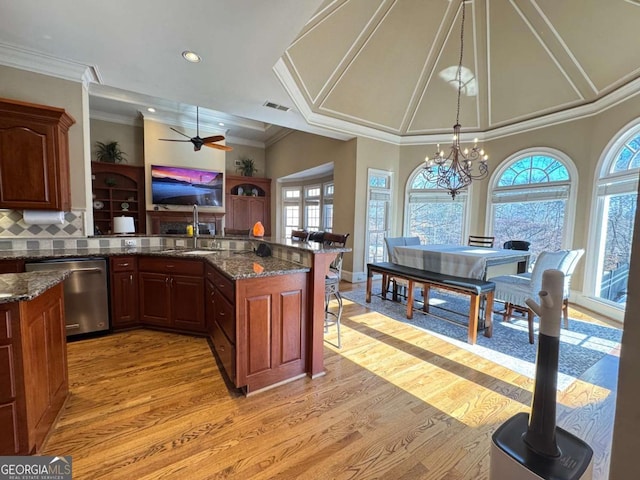 kitchen featuring dark stone countertops, ornamental molding, pendant lighting, stainless steel dishwasher, and sink