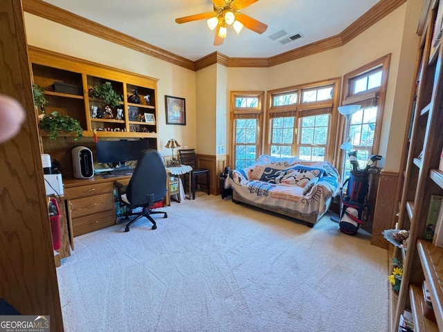 carpeted office space with ceiling fan, ornamental molding, built in desk, and wooden walls