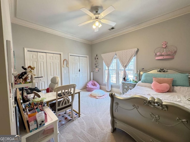 bedroom featuring ceiling fan, light carpet, crown molding, and two closets