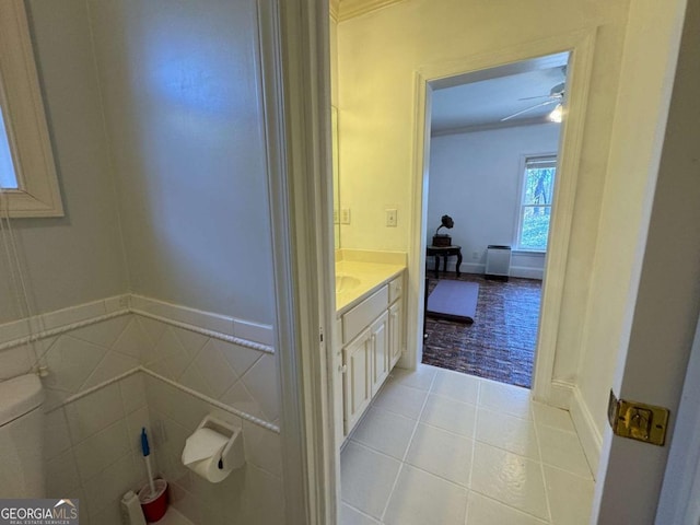 bathroom with toilet, vanity, ceiling fan, tile walls, and tile patterned floors