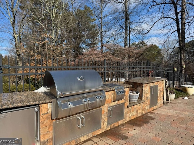 view of patio featuring exterior kitchen and a grill