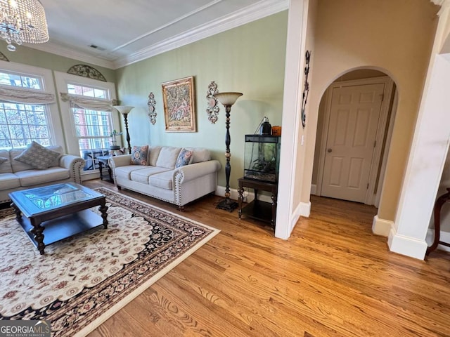 living room with a chandelier, ornamental molding, and light hardwood / wood-style flooring