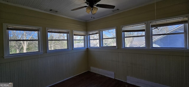 unfurnished room with ceiling fan, dark wood-type flooring, ornamental molding, and wooden walls