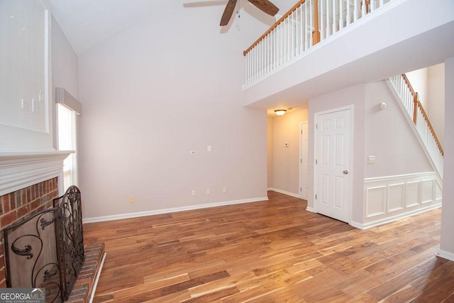 living room with a brick fireplace, hardwood / wood-style flooring, high vaulted ceiling, and ceiling fan