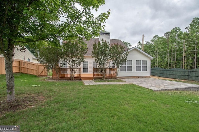 back of house with a lawn, a wooden deck, and a patio