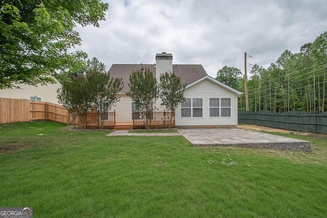 rear view of property with a wooden deck, a lawn, and a patio