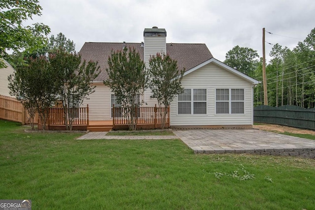 rear view of house with a wooden deck, a lawn, and a patio