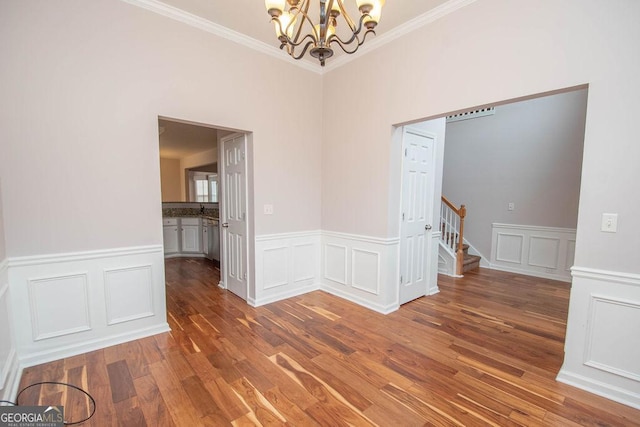 unfurnished room with hardwood / wood-style flooring, crown molding, and a chandelier