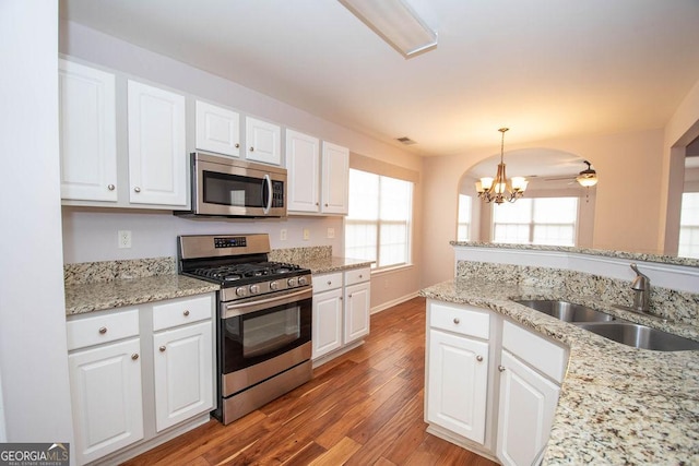 kitchen featuring stainless steel appliances, white cabinetry, decorative light fixtures, and sink