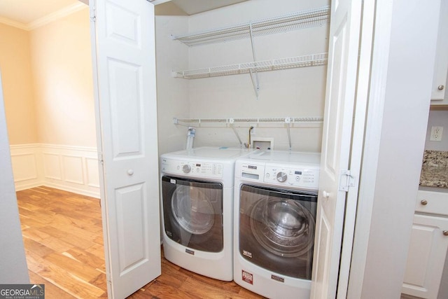 laundry room featuring light wood-type flooring, separate washer and dryer, and crown molding