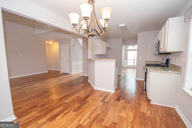 kitchen featuring stainless steel range with gas cooktop, light hardwood / wood-style flooring, hanging light fixtures, white cabinets, and a chandelier