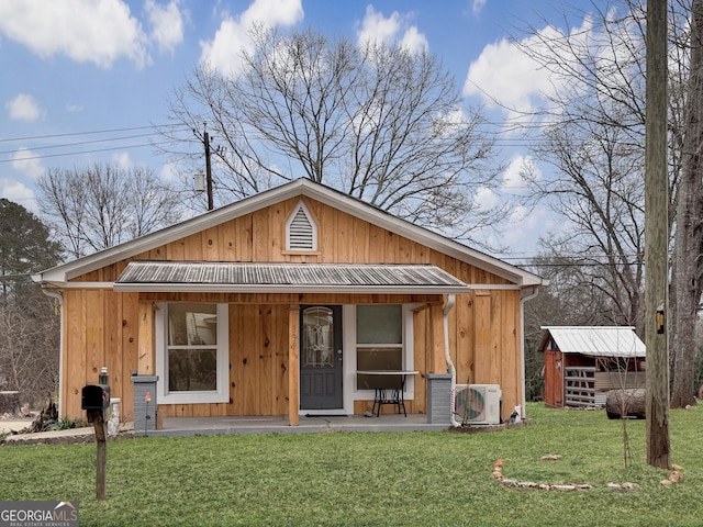 bungalow with a front yard, an outbuilding, and ac unit