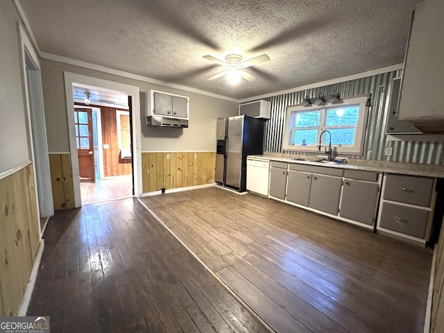 kitchen featuring dishwasher, wood walls, hardwood / wood-style floors, sink, and stainless steel fridge with ice dispenser