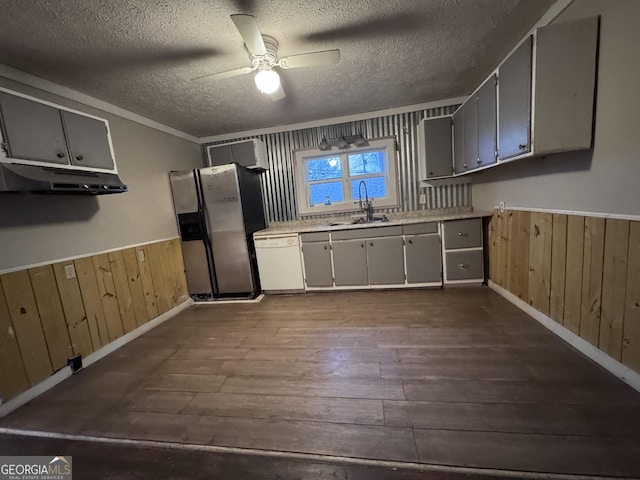 kitchen featuring hardwood / wood-style floors, dishwasher, wooden walls, sink, and stainless steel fridge with ice dispenser