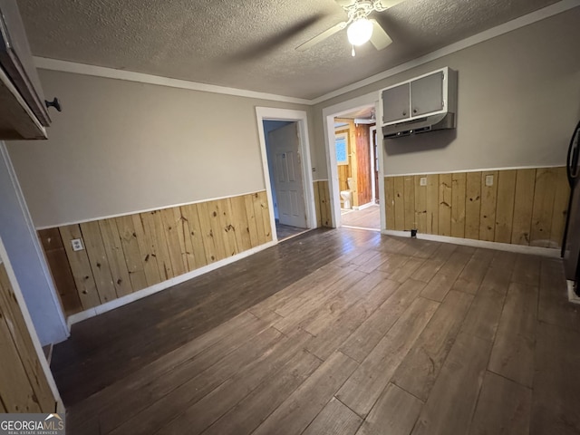 unfurnished room with ceiling fan, a textured ceiling, wood-type flooring, and wooden walls