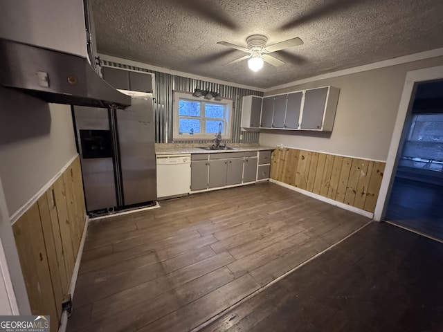 kitchen featuring stainless steel fridge, wooden walls, ceiling fan, dishwasher, and sink