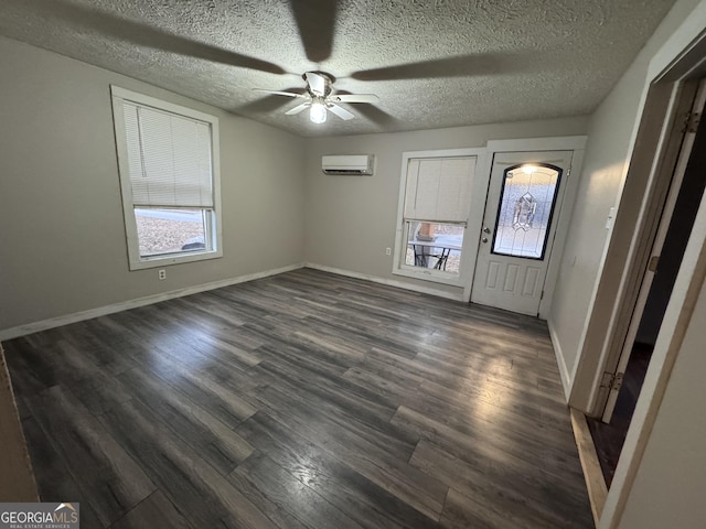 entryway with ceiling fan, an AC wall unit, dark wood-type flooring, and a textured ceiling