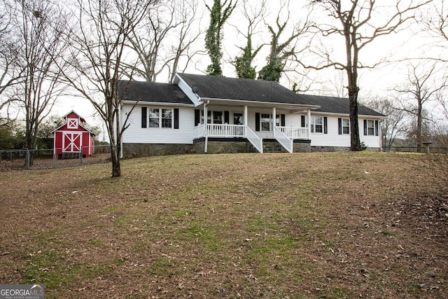 ranch-style house with a front lawn, an outdoor structure, and a porch