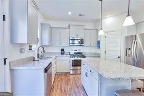 kitchen featuring a kitchen bar, stainless steel appliances, pendant lighting, light hardwood / wood-style flooring, and sink