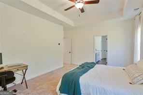 bedroom with ceiling fan, carpet flooring, and a tray ceiling