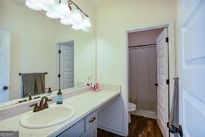 bathroom with curtained shower, hardwood / wood-style floors, toilet, and vanity