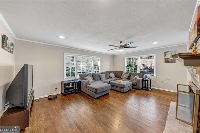 living area featuring a textured ceiling, ornamental molding, a fireplace, and wood finished floors