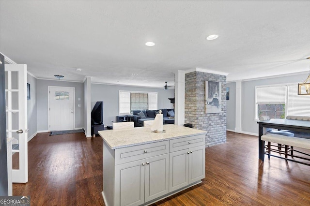 kitchen with open floor plan, light stone counters, dark wood-type flooring, and plenty of natural light