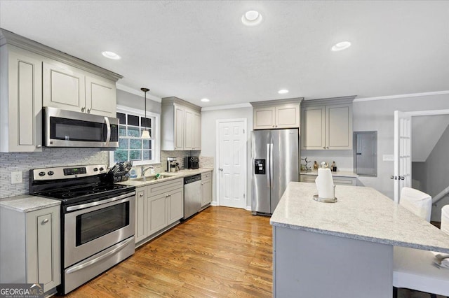 kitchen featuring pendant lighting, appliances with stainless steel finishes, light wood-type flooring, electric panel, and crown molding