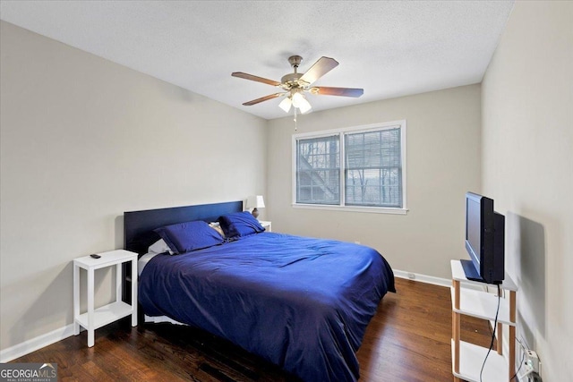 bedroom featuring a textured ceiling, ceiling fan, dark wood-type flooring, and baseboards