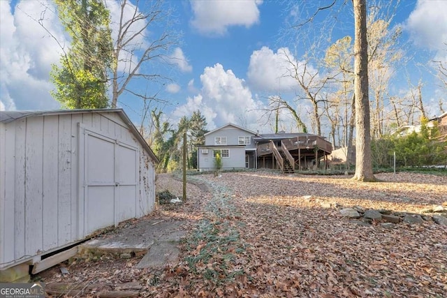 exterior space featuring a shed, stairs, a wooden deck, and an outbuilding