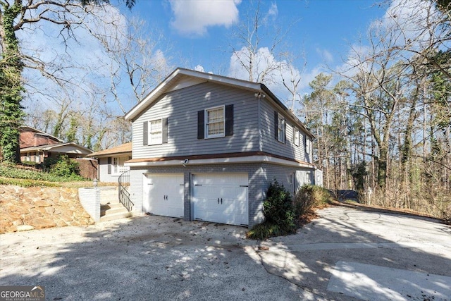 view of home's exterior featuring brick siding, an attached garage, and aphalt driveway