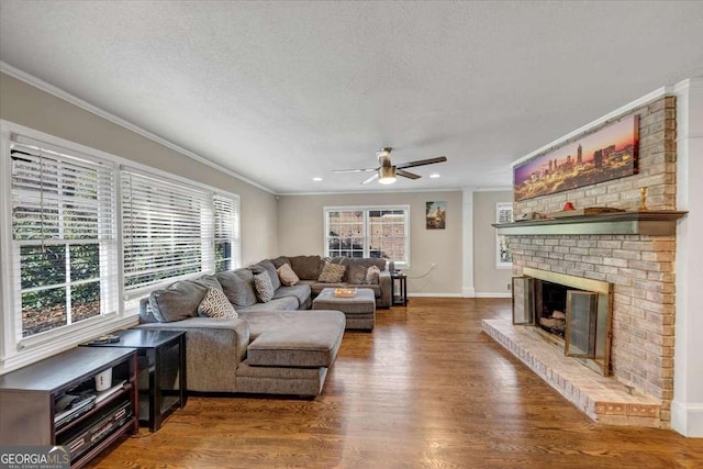 living area featuring a textured ceiling, dark wood-style flooring, a brick fireplace, and crown molding