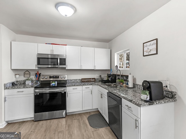 kitchen featuring white cabinetry, stainless steel appliances, sink, and dark stone countertops