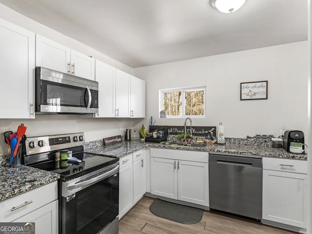 kitchen with appliances with stainless steel finishes, sink, and white cabinets