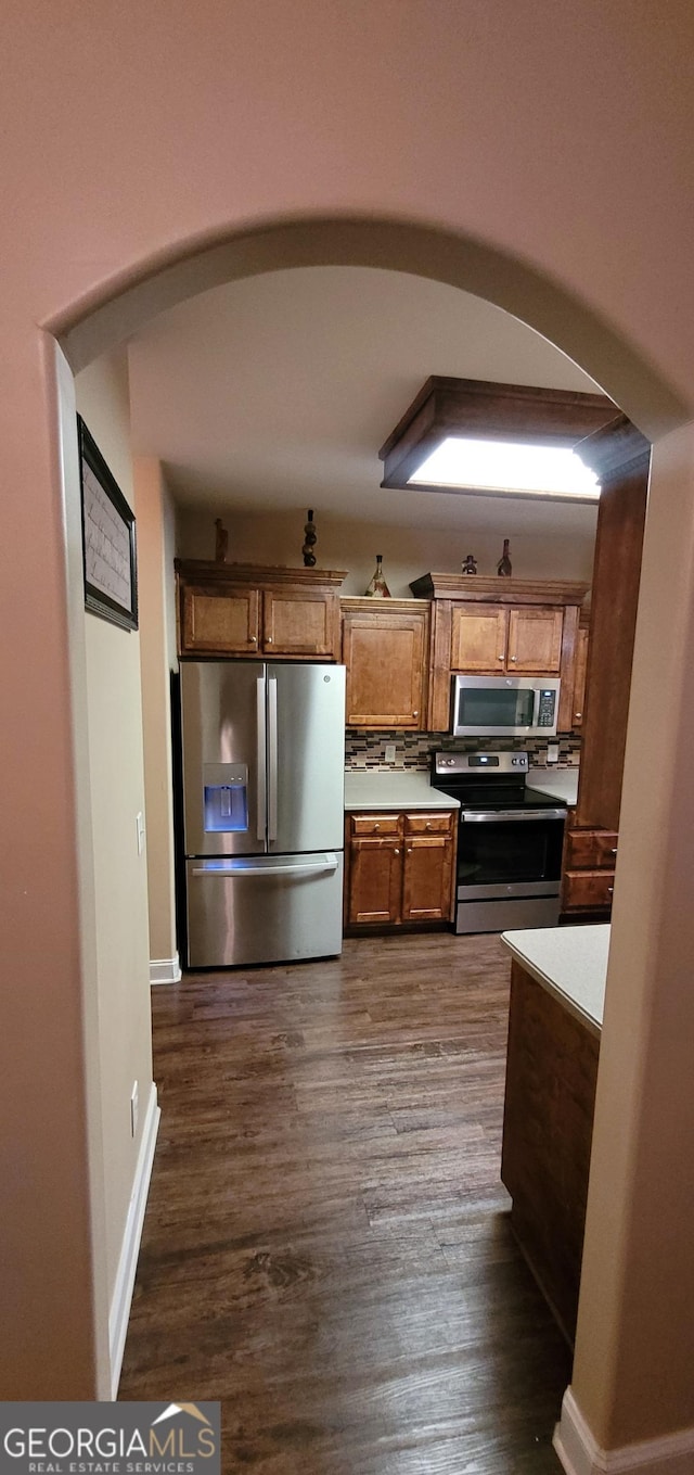 kitchen featuring stainless steel appliances, dark hardwood / wood-style floors, and backsplash