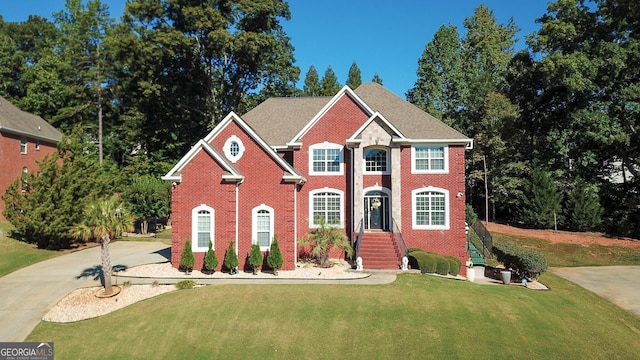 colonial home with brick siding, driveway, and a front lawn