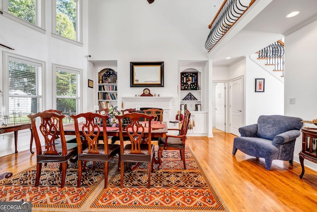 dining space with baseboards, built in features, stairway, light wood-style floors, and a fireplace