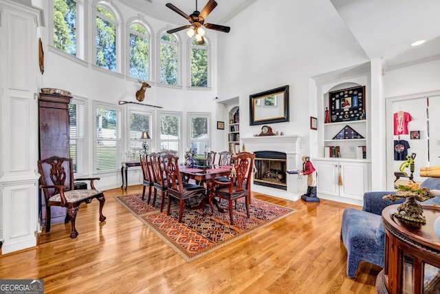 dining area featuring built in shelves, a glass covered fireplace, and light wood-style flooring