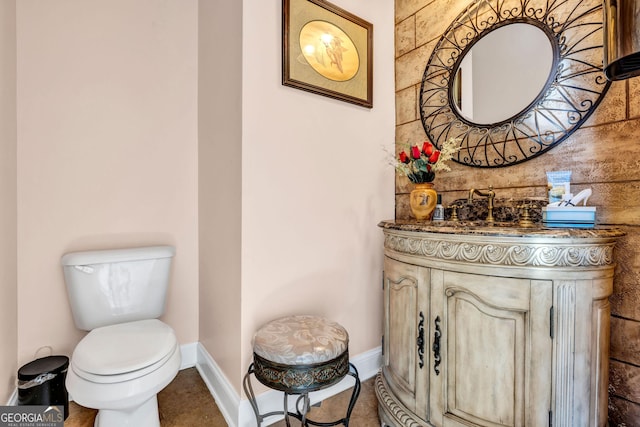 half bathroom featuring baseboards, vanity, and toilet