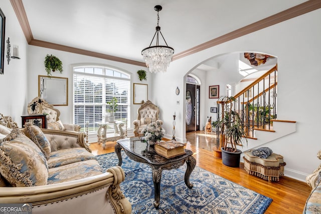 living room featuring arched walkways, a chandelier, wood finished floors, stairs, and ornamental molding