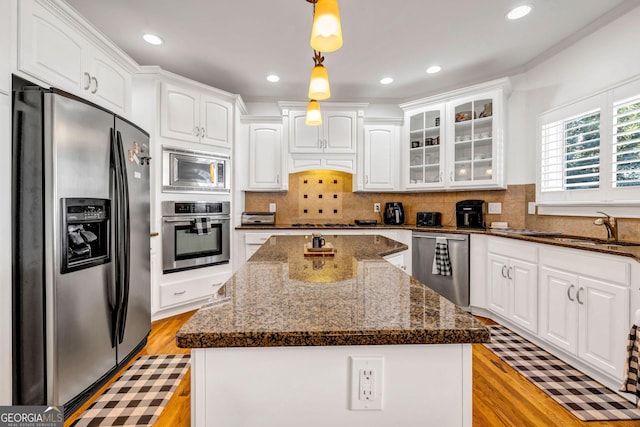 kitchen with stainless steel appliances, a sink, white cabinetry, and a center island