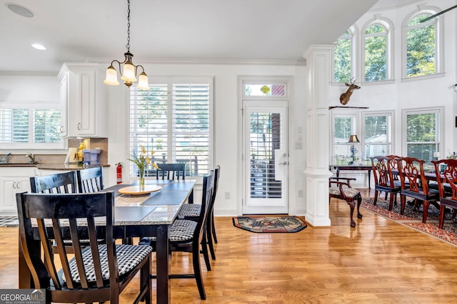 dining area with ornamental molding, plenty of natural light, light wood finished floors, and an inviting chandelier