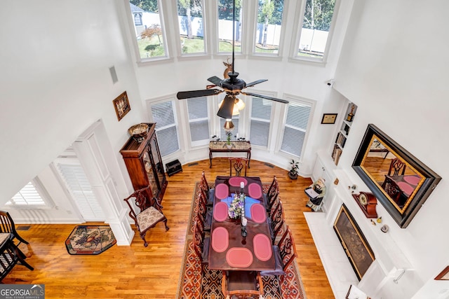 living area with a towering ceiling and light wood-style flooring