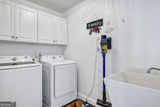 washroom featuring baseboards, a sink, cabinet space, and washer and dryer